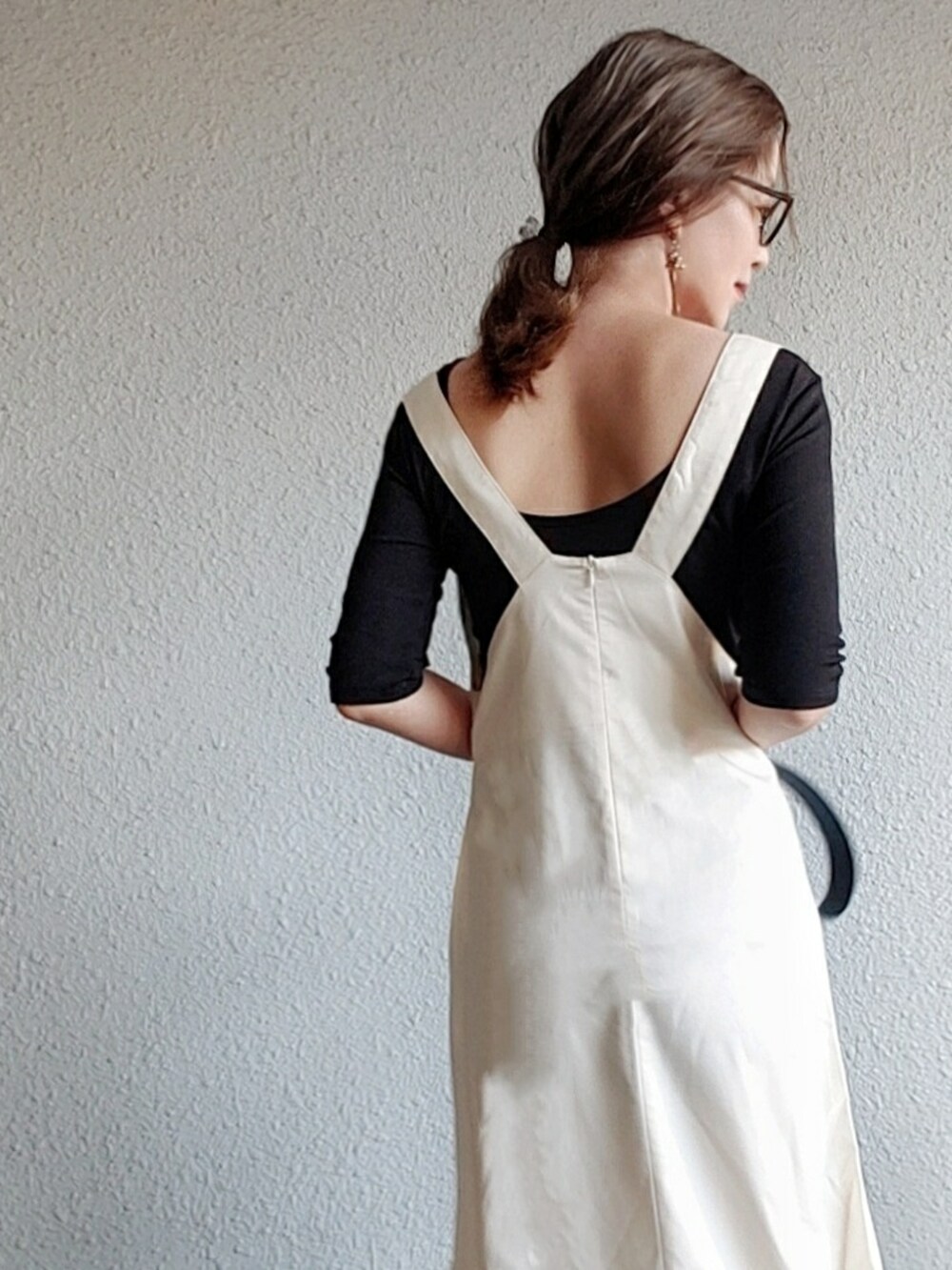 ホワイト系のジャンパースカート、ブラック系のTシャツ/カットソー、ブラック系のサンダルを着用したレディースの春コーディネートの3枚目の写真