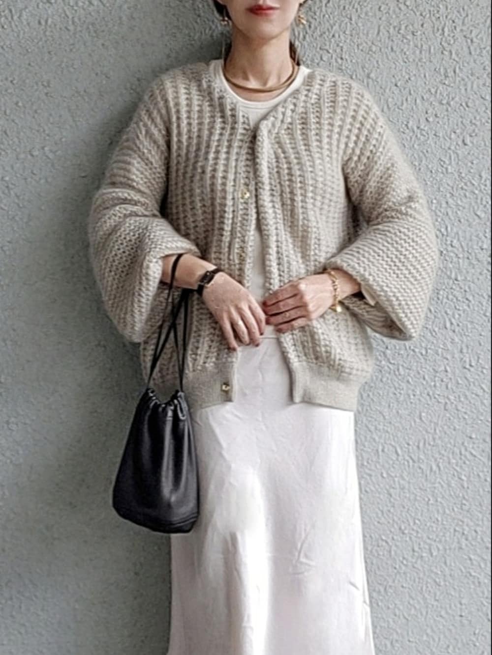 グレー系のカーディガン/ボレロ、ブラック系のバッグ、ホワイト系のスカートを着用したレディースの春コーディネートの4枚目の写真