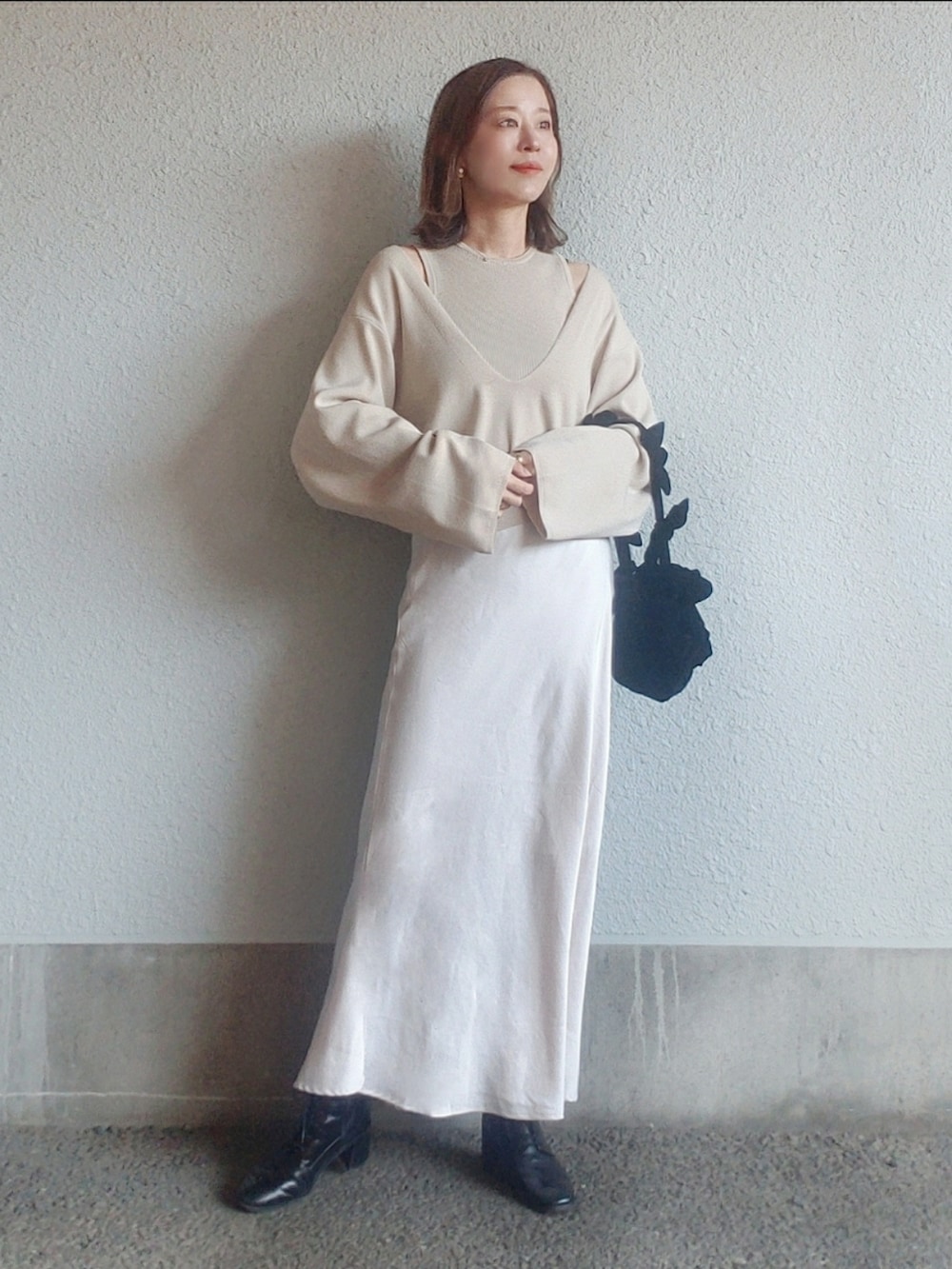 ベージュ系のニット/セーター、ブラック系のバッグ、ホワイト系のスカートを着用したレディースの春コーディネートの3枚目の写真