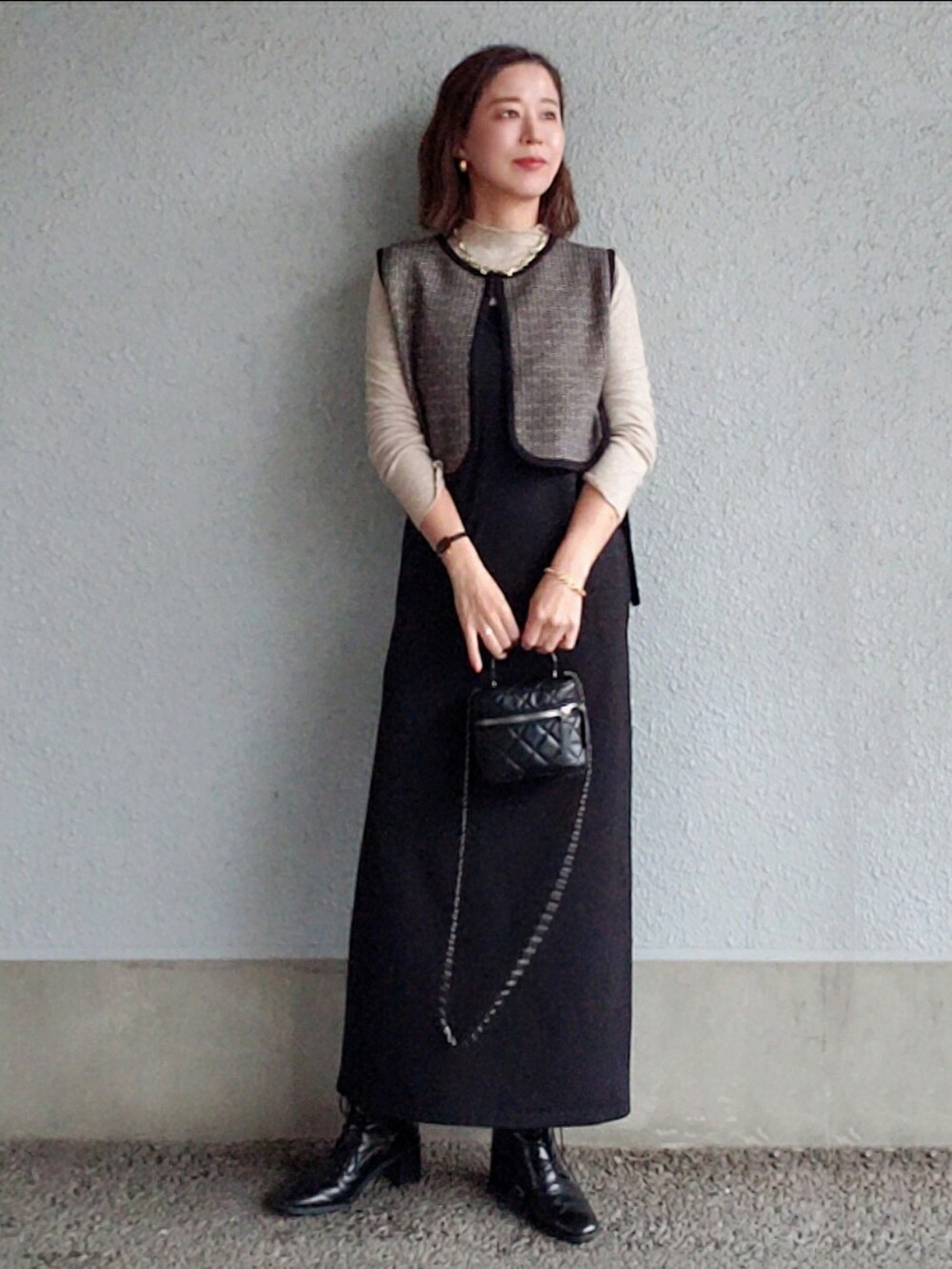 ブラック系のワンピース、ブラック系のベスト、ブラック系のブーツを着用したレディースの冬コーディネートの4枚目の写真