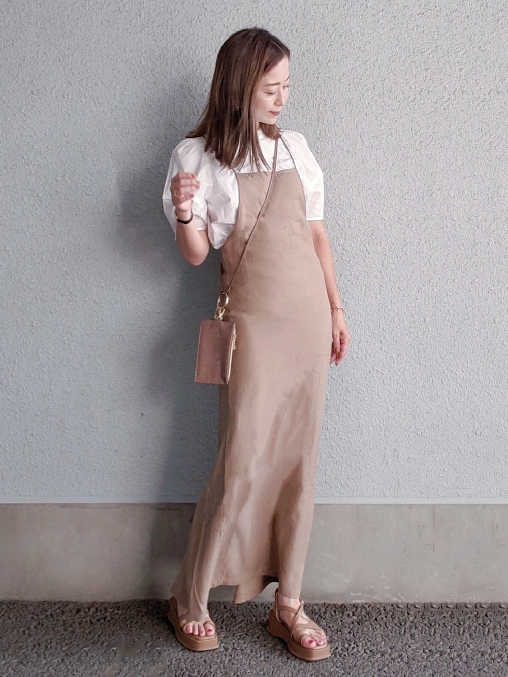 ベージュ系のワンピース、ブラウン系のサンダル、ホワイト系のシャツ/ブラウスを着用したレディースの夏コーディネートの3枚目の写真