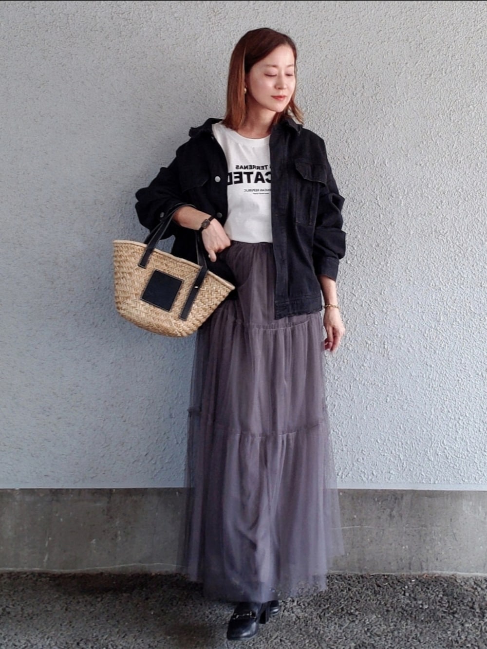ブラック系のブルゾン、ブラック系のかごバッグ、グレー系のスカートを着用したレディースの春コーディネートの2枚目の写真