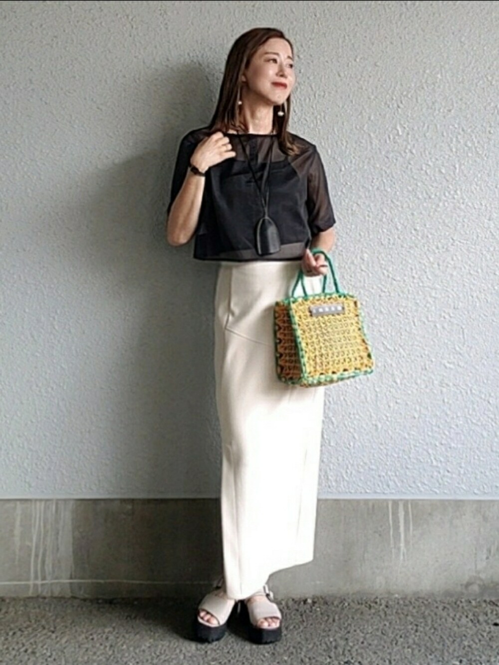 ブラック系のトップス、ベージュ系のスカート、グレー系のサンダルを着用したレディースの夏コーディネートの3枚目の写真