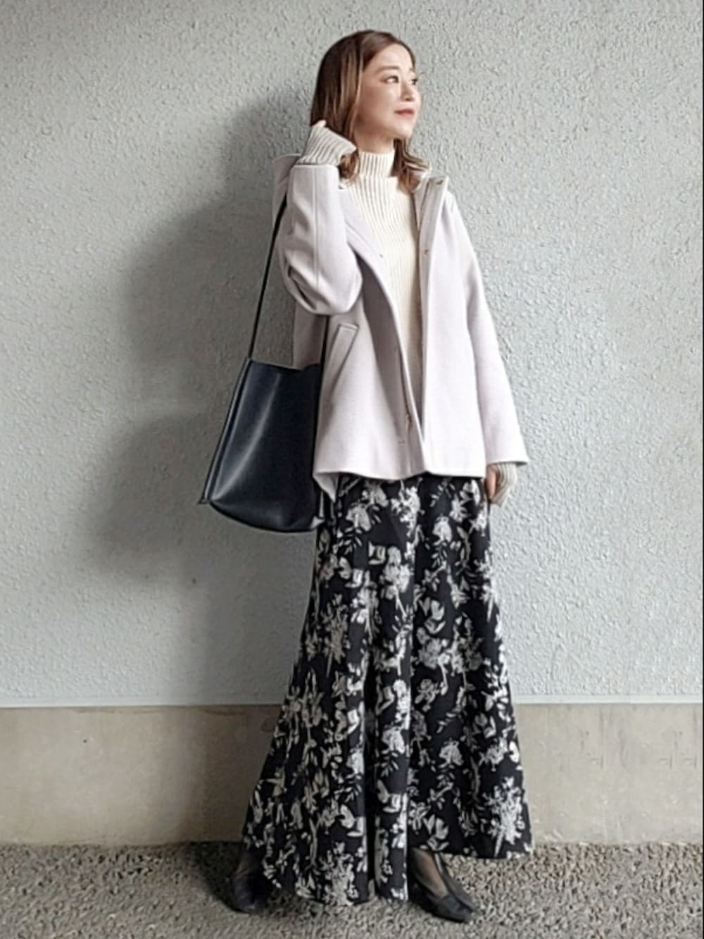 グレー系のノーカラーコート、ブラック系のスカート、ブラック系のブーツを着用したレディースの秋コーディネートの4枚目の写真