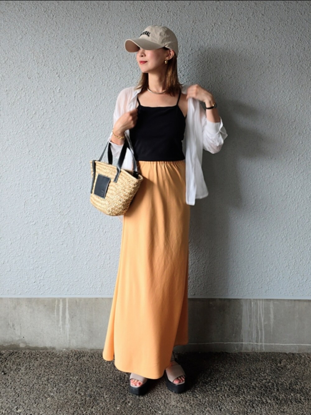 ブラック系のキャミソール、オレンジ系のスカート、ブラック系のかごバッグを着用したレディースの夏コーディネートの2枚目の写真