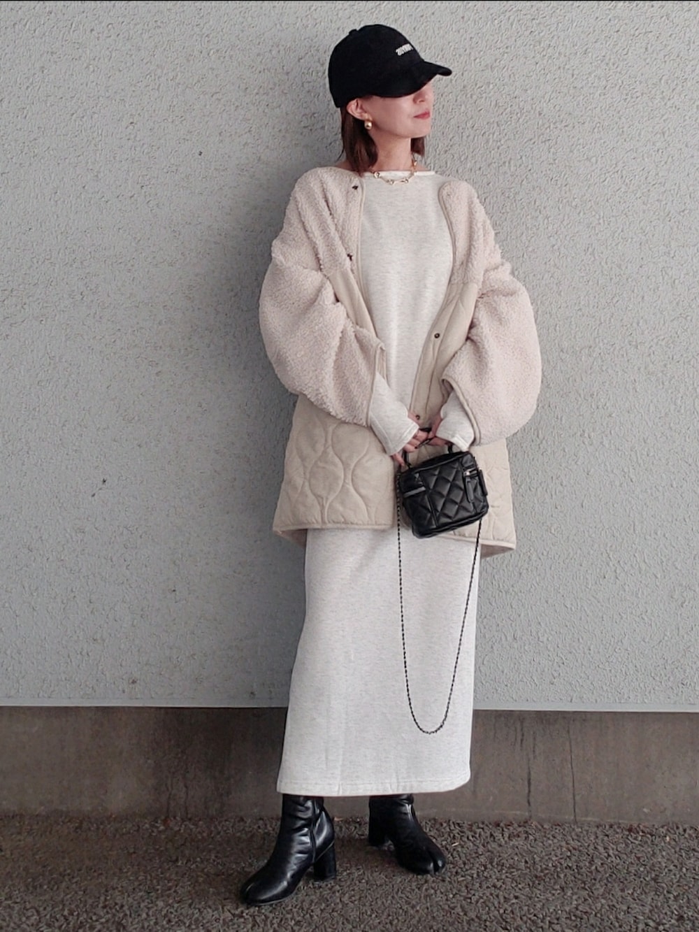 ベージュ系のワンピース、ホワイト系のブルゾン、ブラック系のブーツを着用したレディースの冬コーディネートの3枚目の写真