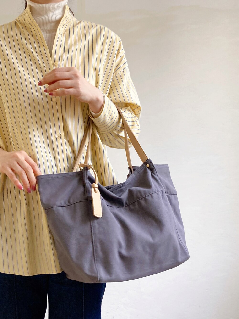 イエロー系のシャツ/ブラウス、グレー系のトートバッグ、ブルー系のデニムパンツを着用したレディースの冬コーディネートの2枚目の写真