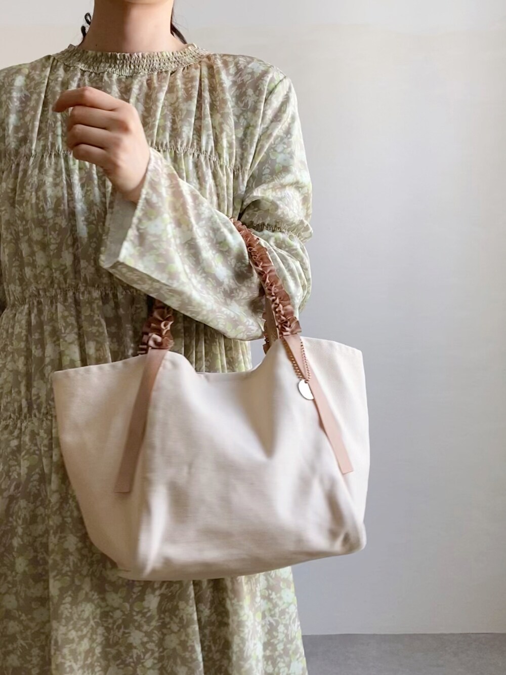 イエロー系のワンピース、ホワイト系のトートバッグ、グレー系のパンプスを着用したレディースの春コーディネートの2枚目の写真