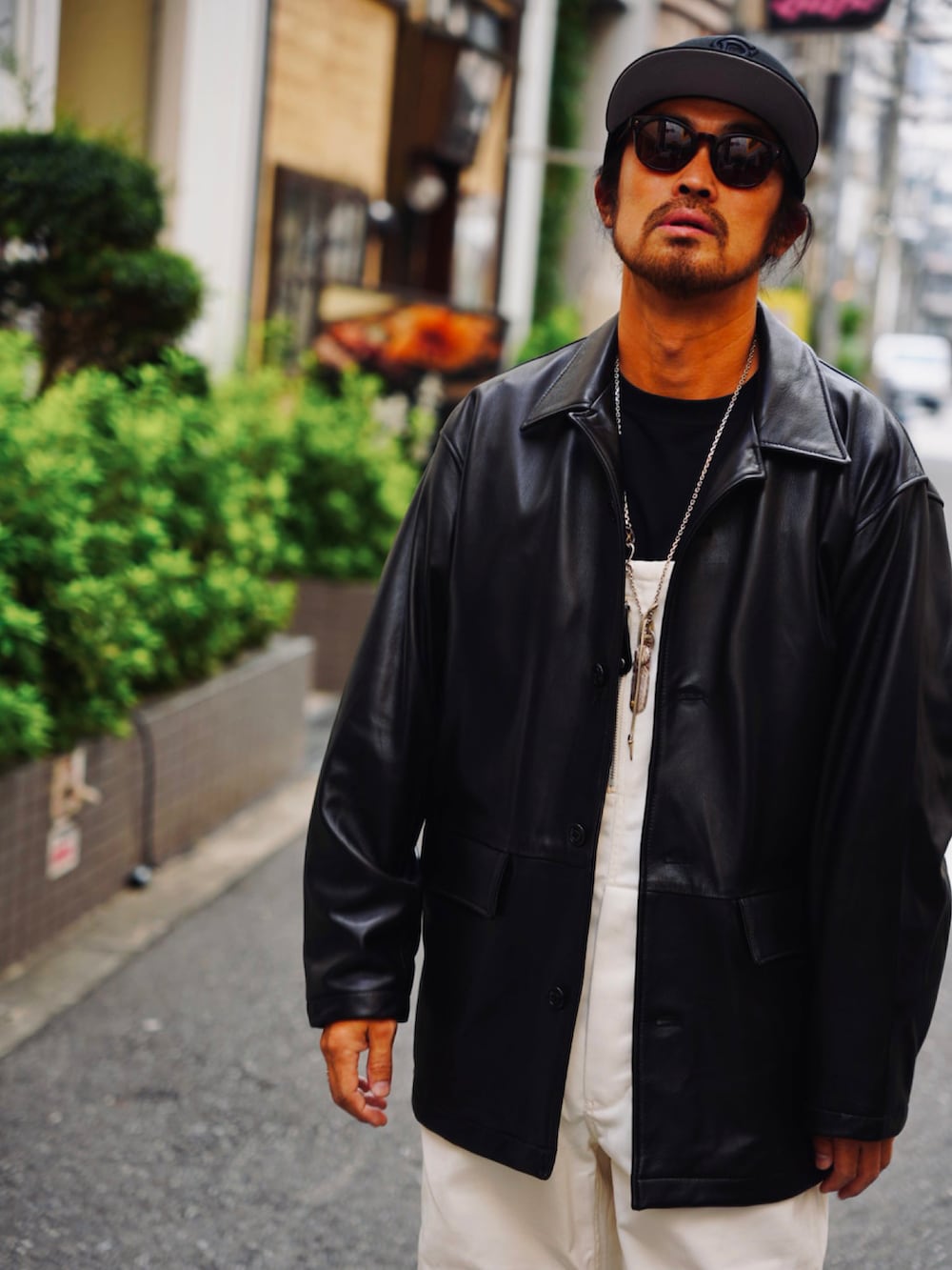 ブラック系のライダースジャケット、ブラック系のTシャツ/カットソー、ホワイト系のサロペット/オーバーオールを着用したメンズの秋コーディネートの3枚目の写真