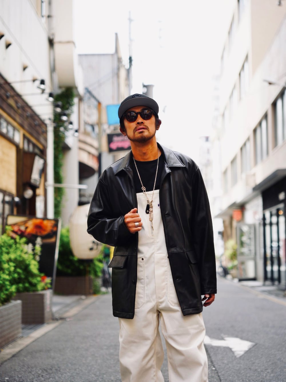 ブラック系のライダースジャケット、ブラック系のTシャツ/カットソー、ホワイト系のサロペット/オーバーオールを着用したメンズの秋コーディネートの2枚目の写真