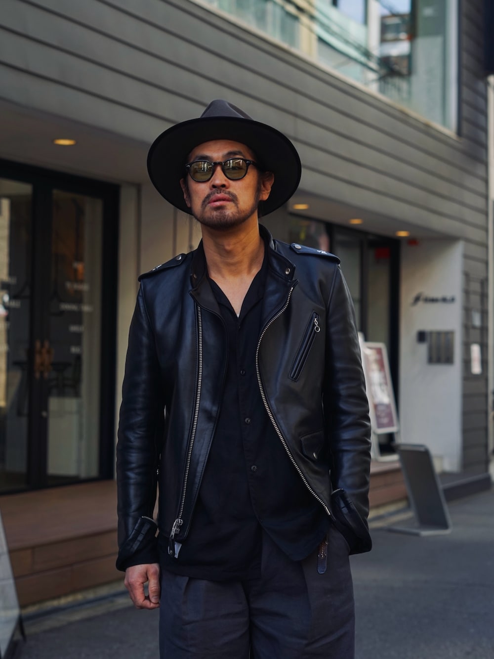 ブラック系のライダースジャケット、ブラック系のシャツ/ブラウス、ブラック系のチノパンツを着用したメンズの春コーディネートの2枚目の写真