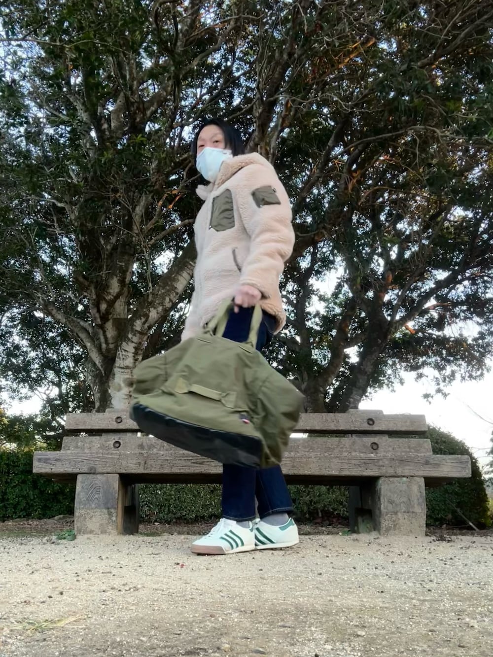 ベージュ系のマウンテンパーカー、ブルー系のデニムパンツ、グリーン系のトートバッグを着用したメンズの冬コーディネートの2枚目の写真