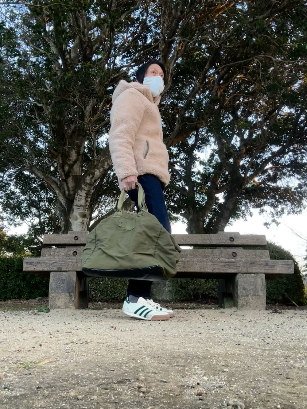 ベージュ系のマウンテンパーカー、ブルー系のデニムパンツ、グリーン系のトートバッグを着用したメンズの冬コーディネートの3枚目の写真