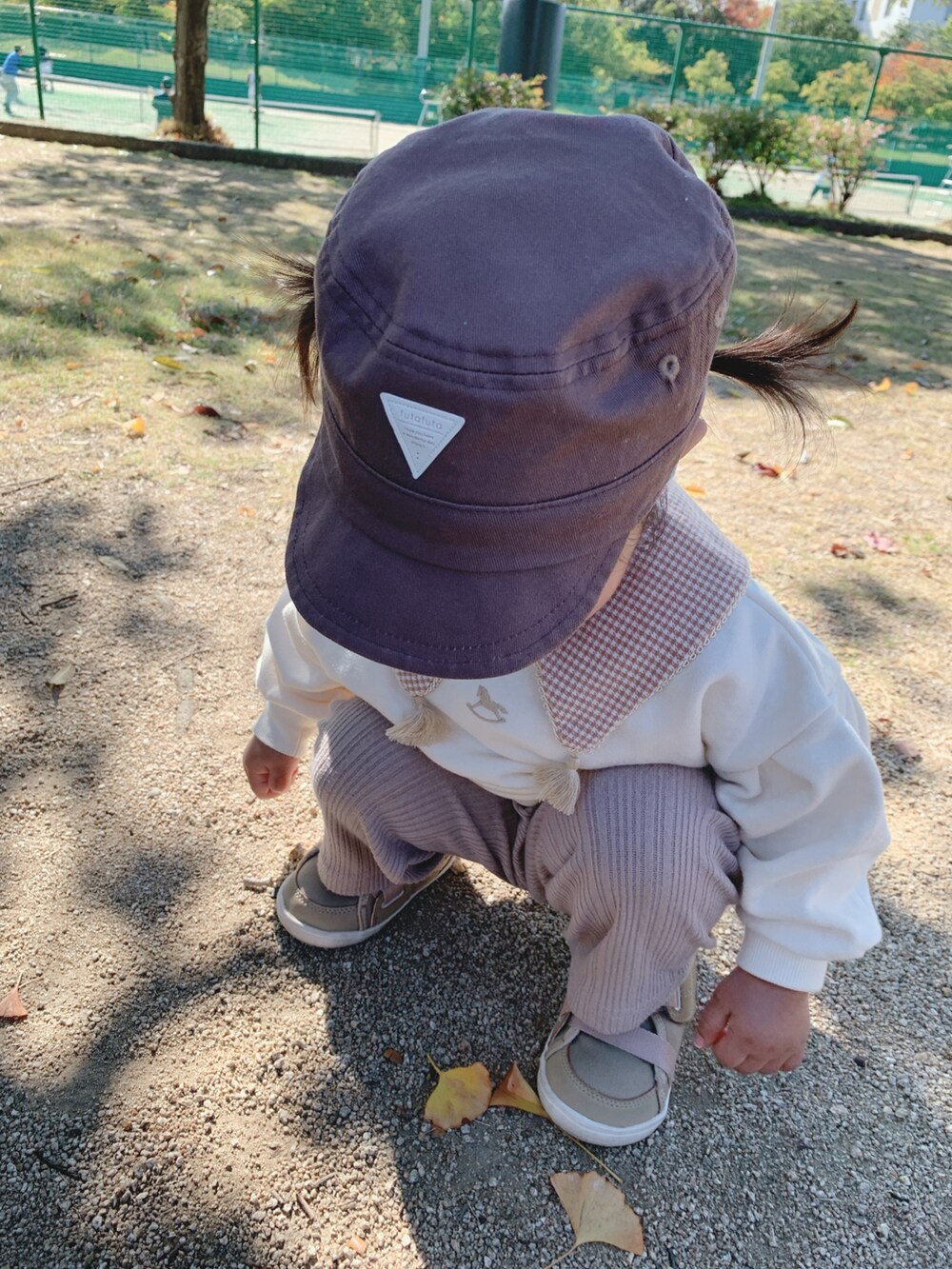 ホワイト系のトップス、ベージュ系のスニーカー、ブラウン系のキャップを着用したキッズの秋コーディネートの2枚目の写真