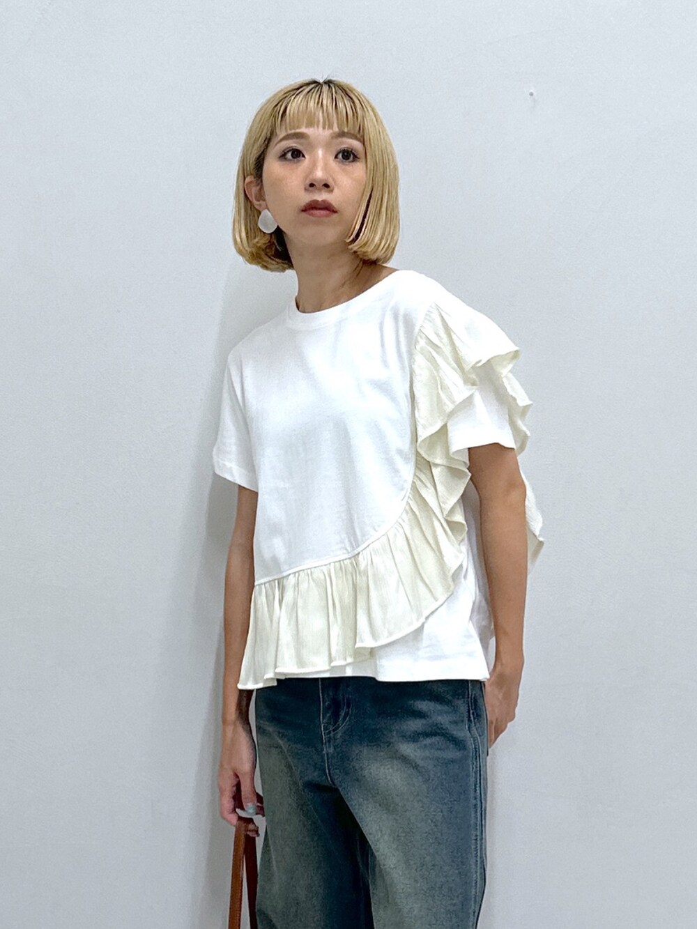 ブルー系のデニムパンツ、ホワイト系のTシャツ/カットソー、ベージュ系のショルダーバッグを着用したレディースの夏コーディネートの4枚目の写真