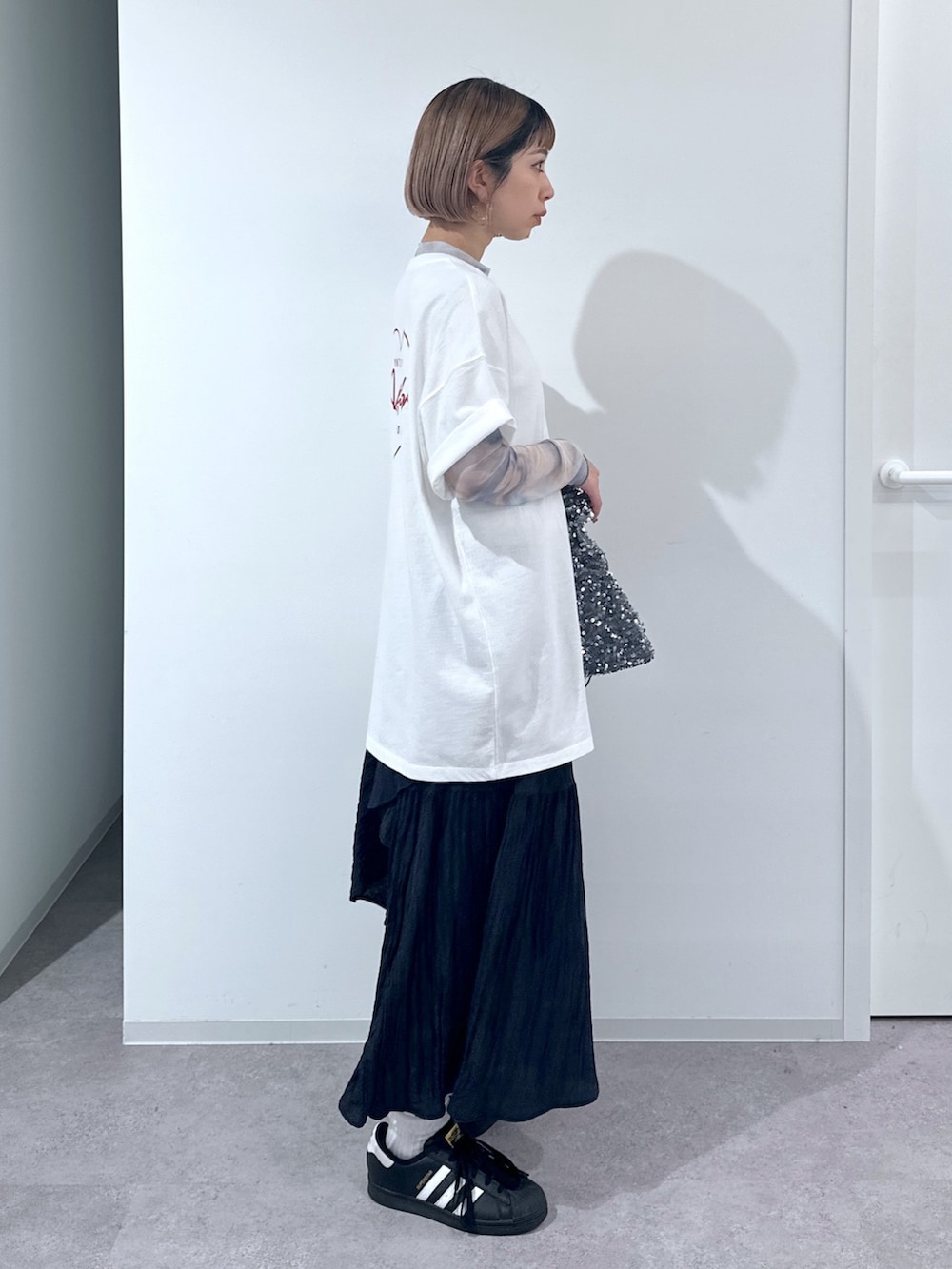 ホワイト系のTシャツ/カットソー、オレンジ系のTシャツ/カットソー、ブラック系のスカートを着用したレディースの春コーディネートの2枚目の写真