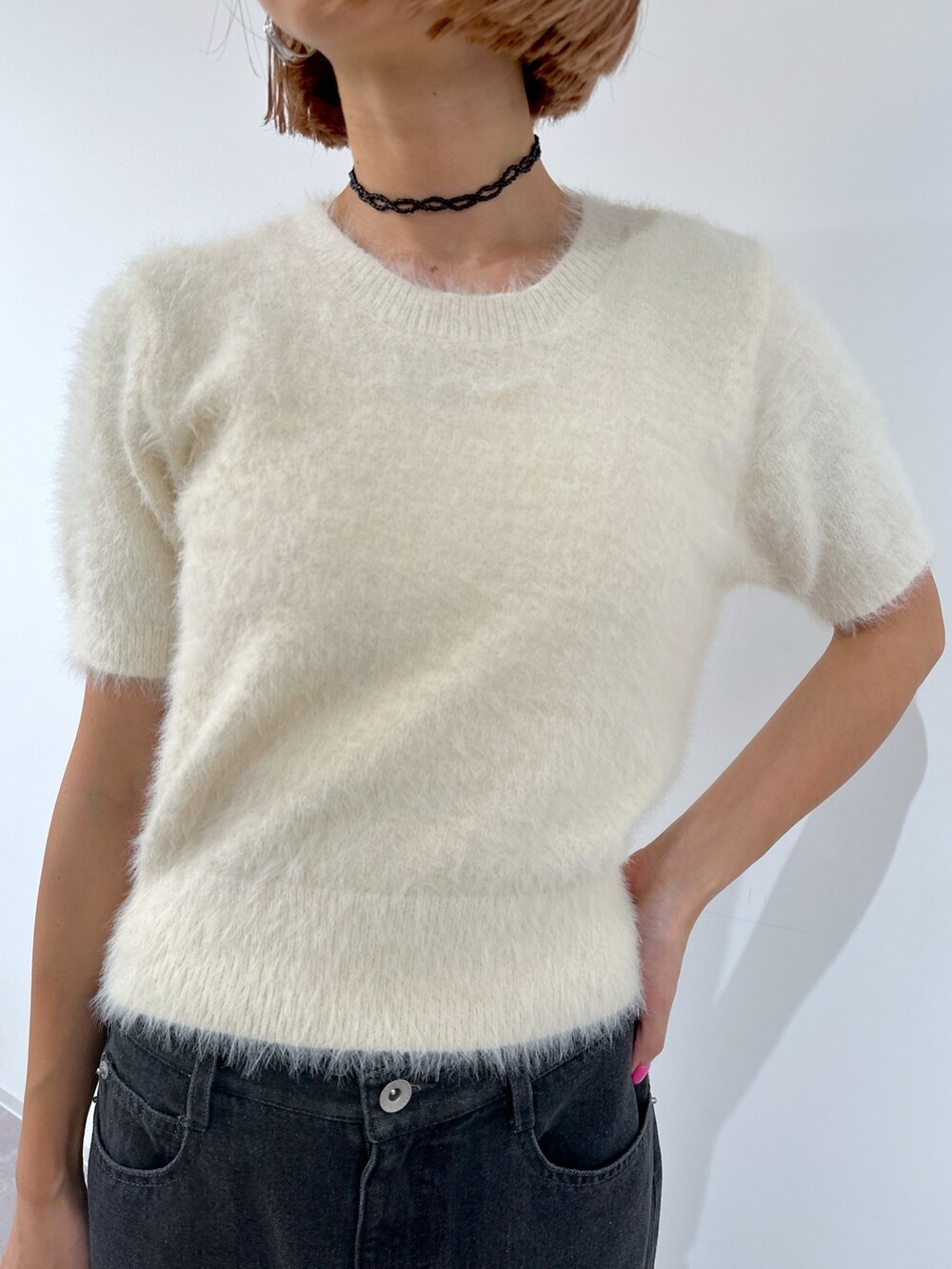 ブラック系のショルダーバッグ、ホワイト系のニット/セーター、ブラック系のデニムスカートを着用したレディースの春コーディネートの4枚目の写真