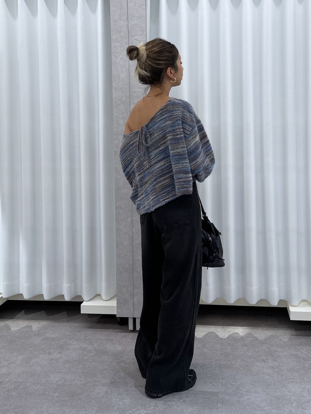ブルー系のニット/セーター、ブラック系のデニムパンツ、ブラック系のショルダーバッグを着用したレディースの夏コーディネートの3枚目の写真