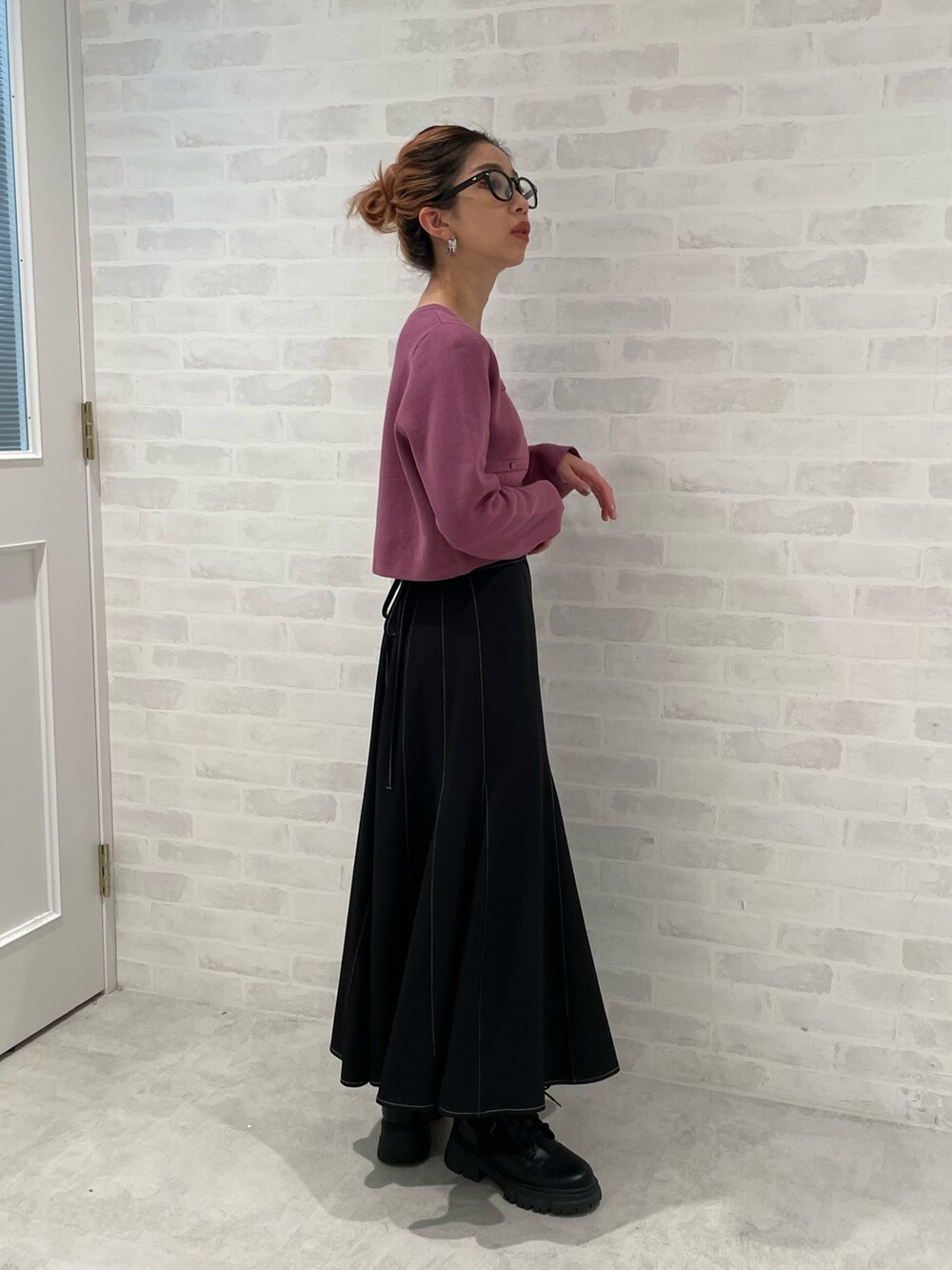 ブラック系のスカート、パープル系のニット/セーター、ブラック系のブーツを着用したレディースの秋コーディネートの2枚目の写真