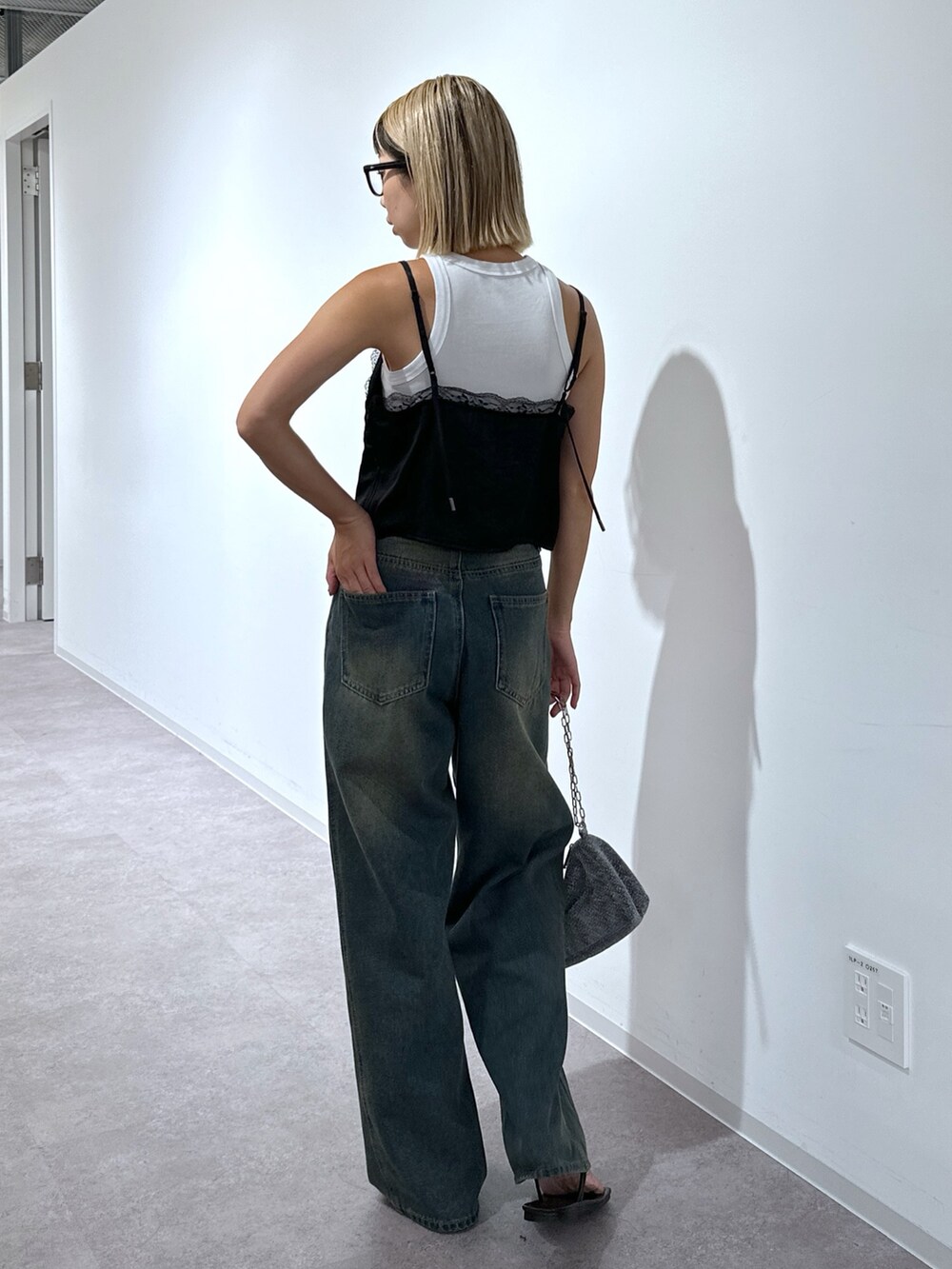 ブラック系のキャミソール、ブルー系のデニムパンツ、シルバー系のハンドバッグを着用したレディースの秋コーディネートの3枚目の写真