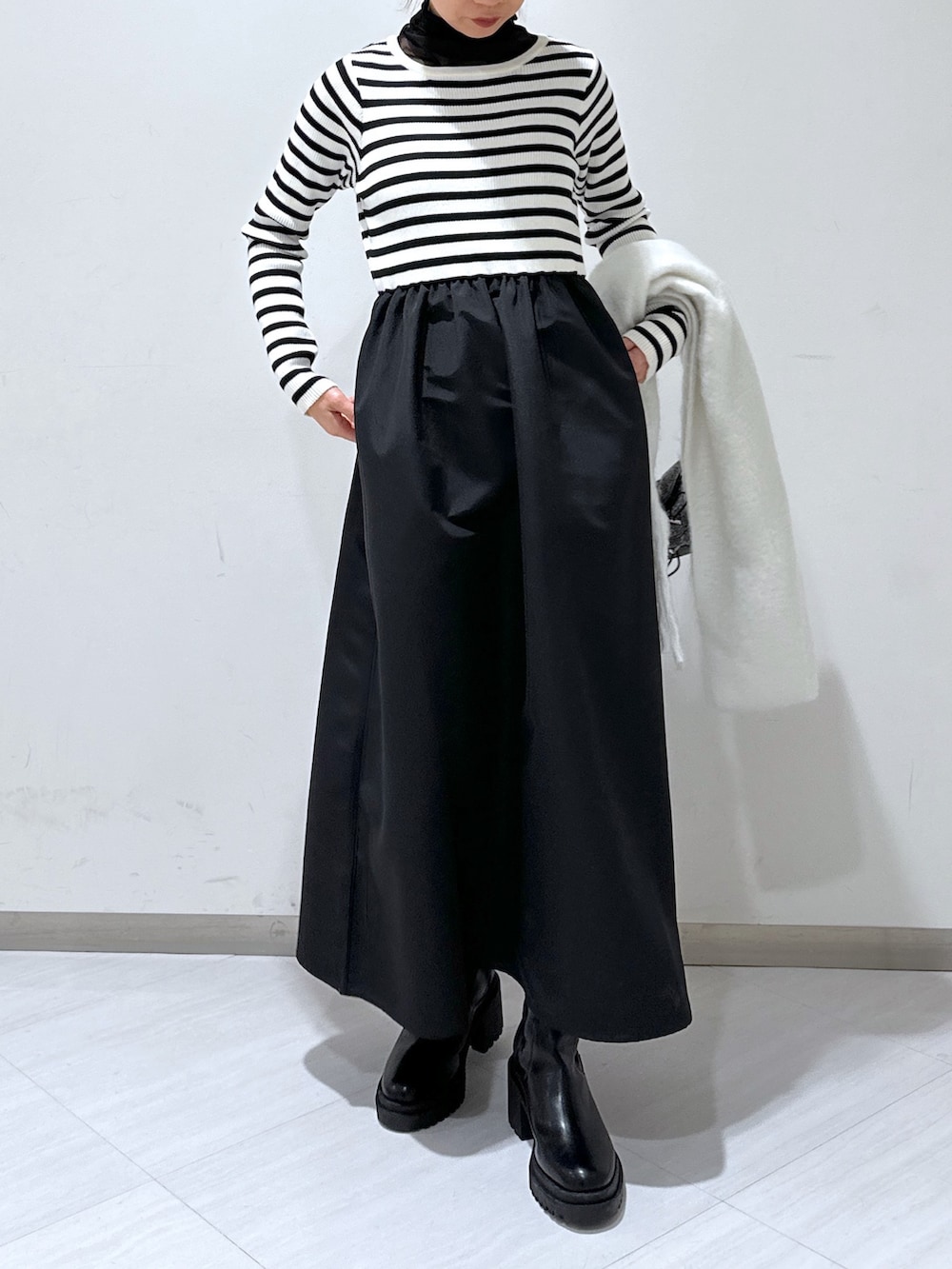 ブラック系のステンカラーコート、ブラック系のワンピース、ブラック系のTシャツ/カットソーを着用したレディースの冬コーディネートの5枚目の写真