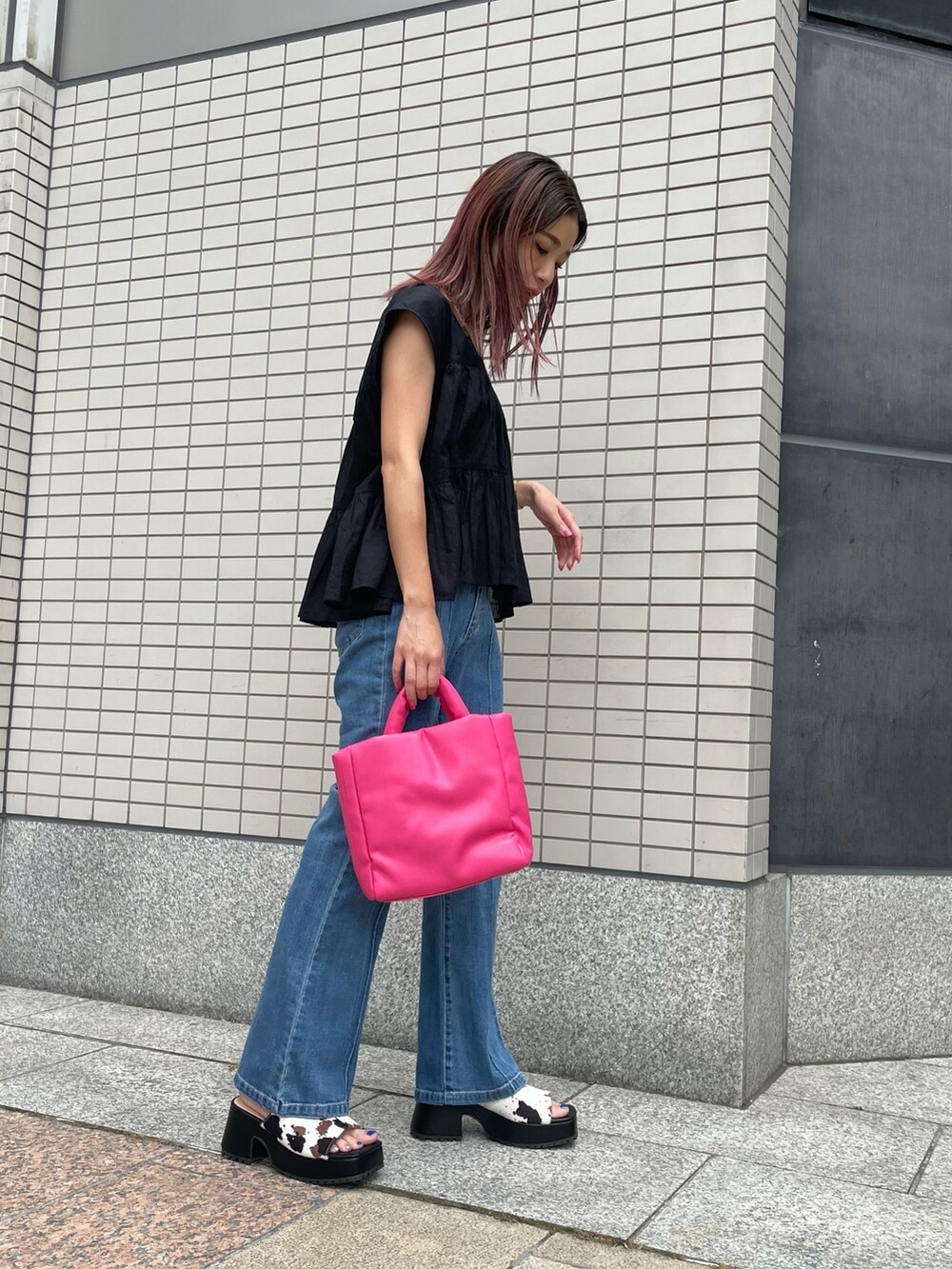 ホワイト系のサンダル、ブルー系のデニムパンツ、ピンク系のショルダーバッグを着用したレディースの夏コーディネートの2枚目の写真