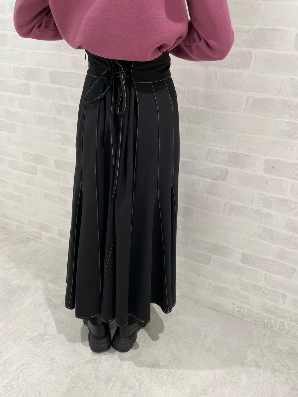 ブラック系のスカート、パープル系のニット/セーター、ブラック系のブーツを着用したレディースの秋コーディネートの5枚目の写真