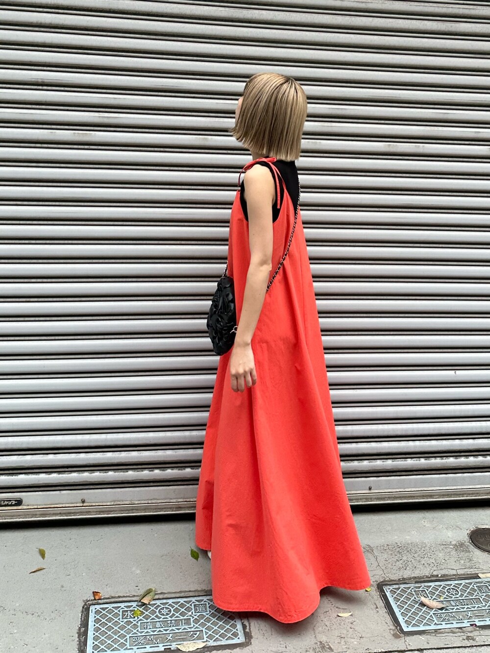 レッド系のワンピース、ブラック系のハンドバッグを着用したレディースの夏コーディネートの2枚目の写真