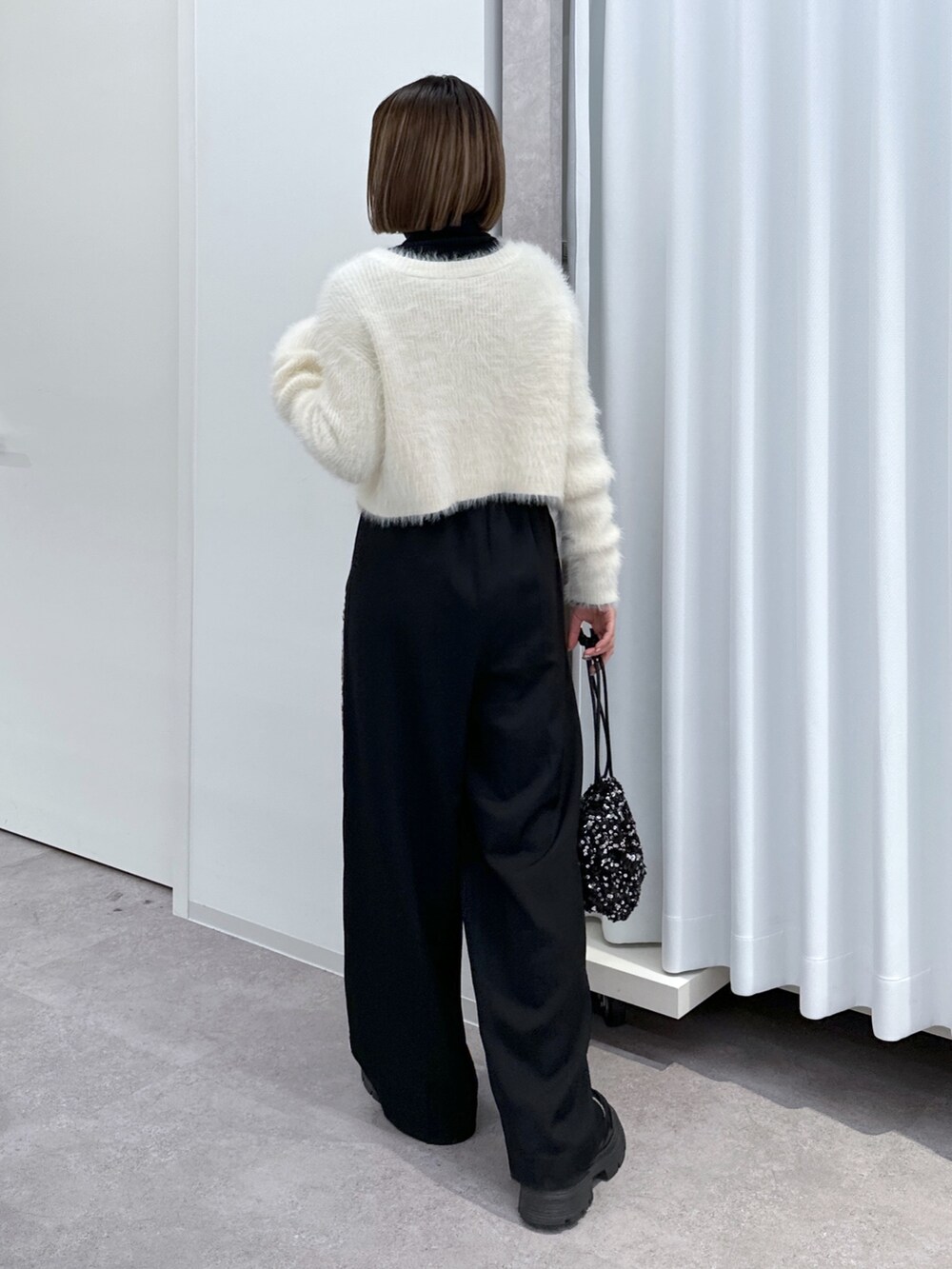 ブラック系のその他パンツ、ブラック系のハンドバッグ、ホワイト系のカーディガン/ボレロを着用したレディースの冬コーディネートの6枚目の写真