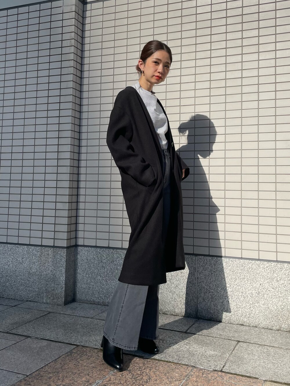 ブラック系のデニムパンツ、ブラック系のノーカラーコートを着用したレディースの夏コーディネートの3枚目の写真