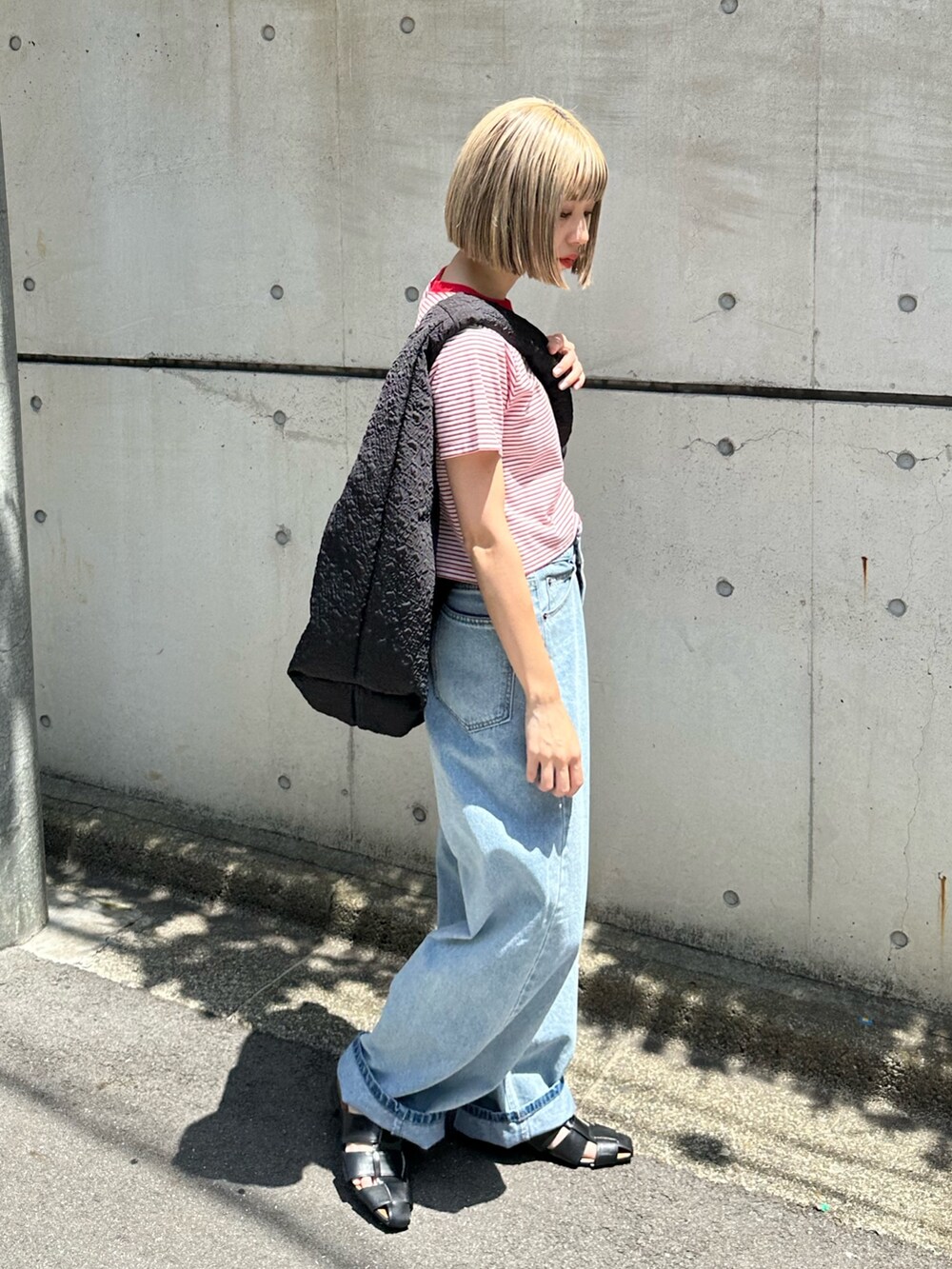 ブルー系のデニムパンツ、ブラック系のサンダル、ブラック系のショルダーバッグを着用したレディースの春コーディネートの2枚目の写真