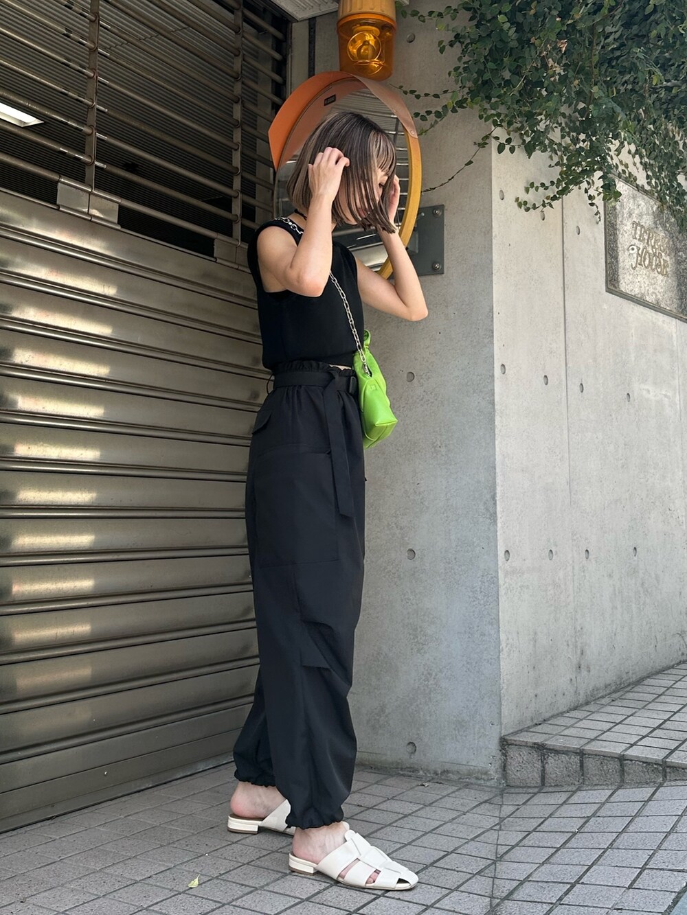 ブラック系のベスト、ブラック系のカーゴパンツ、ホワイト系のサンダルを着用したレディースの夏コーディネートの3枚目の写真