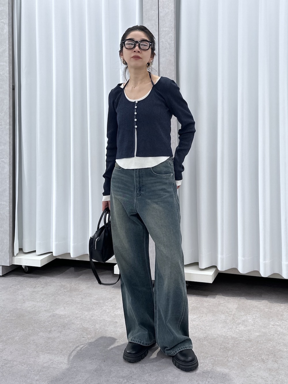 ブルー系のニット/セーター、ブルー系のデニムパンツ、ブラック系のハンドバッグを着用したレディースの春コーディネートの8枚目の写真