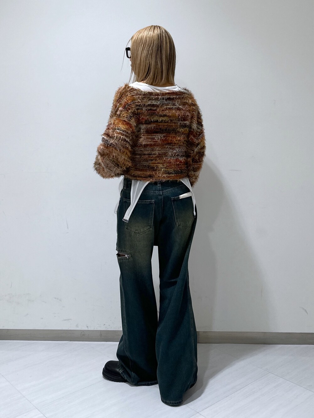 ブルー系のデニムパンツ、レッド系のニット/セーター、ブラック系のショルダーバッグを着用したレディースの秋コーディネートの3枚目の写真