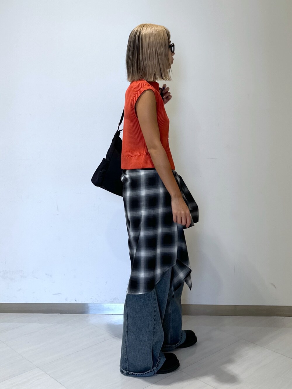 オレンジ系のニット/セーター、ブラック系のシャツ/ブラウス、ブルー系のデニムパンツを着用したレディースの秋コーディネートの2枚目の写真