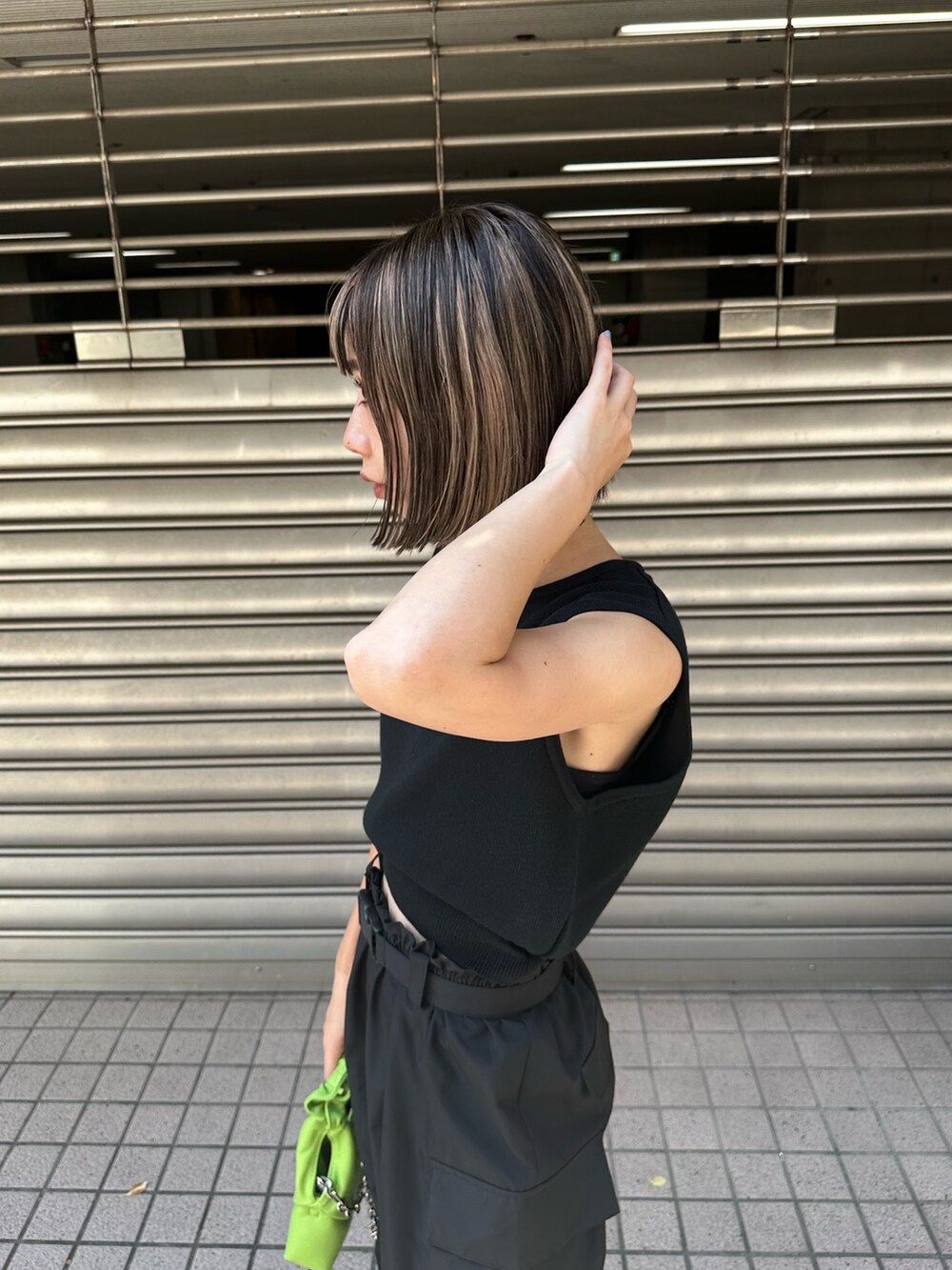 ブラック系のベスト、ブラック系のカーゴパンツ、ホワイト系のサンダルを着用したレディースの夏コーディネートの5枚目の写真