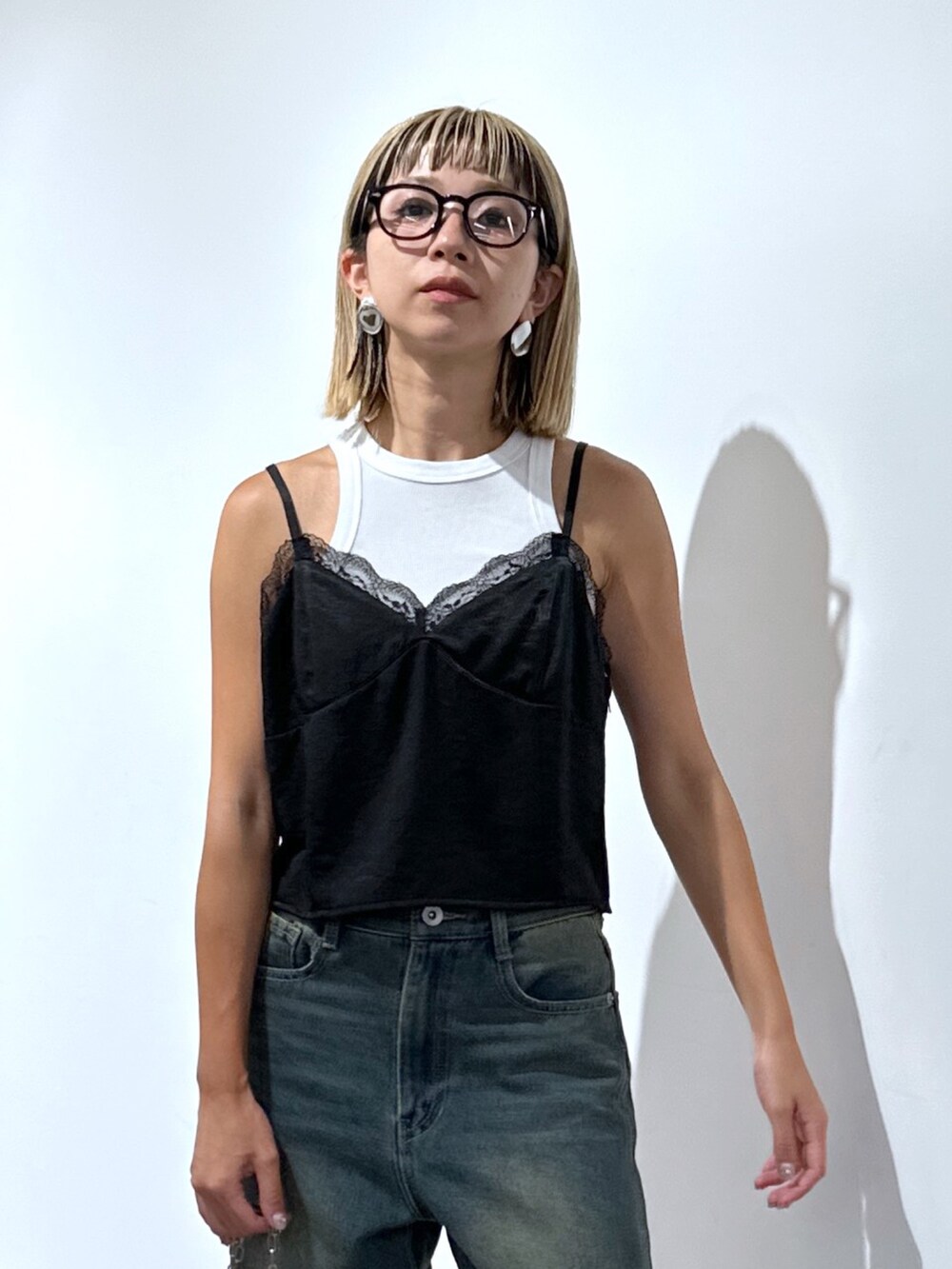 ブラック系のキャミソール、ブルー系のデニムパンツ、シルバー系のハンドバッグを着用したレディースの秋コーディネートの4枚目の写真