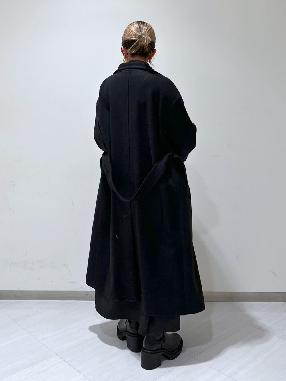 ブラック系のステンカラーコート、ブラック系のワンピース、ブラック系のTシャツ/カットソーを着用したレディースの冬コーディネートの3枚目の写真