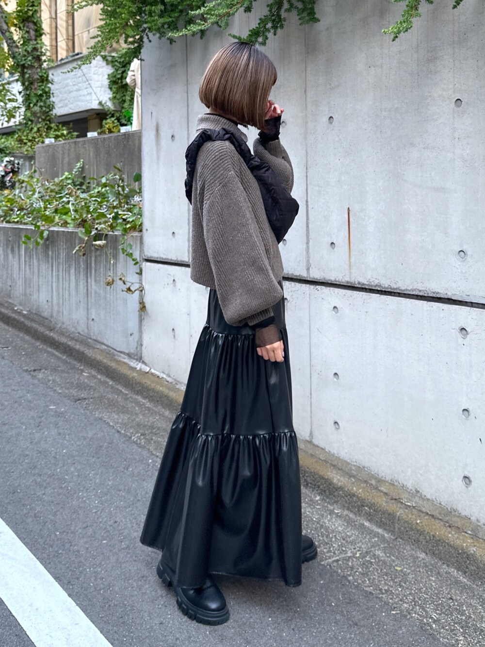 ブラック系のショルダーバッグ、ブラウン系のワンピース、ブラック系のスカートを着用したレディースの秋コーディネートの2枚目の写真