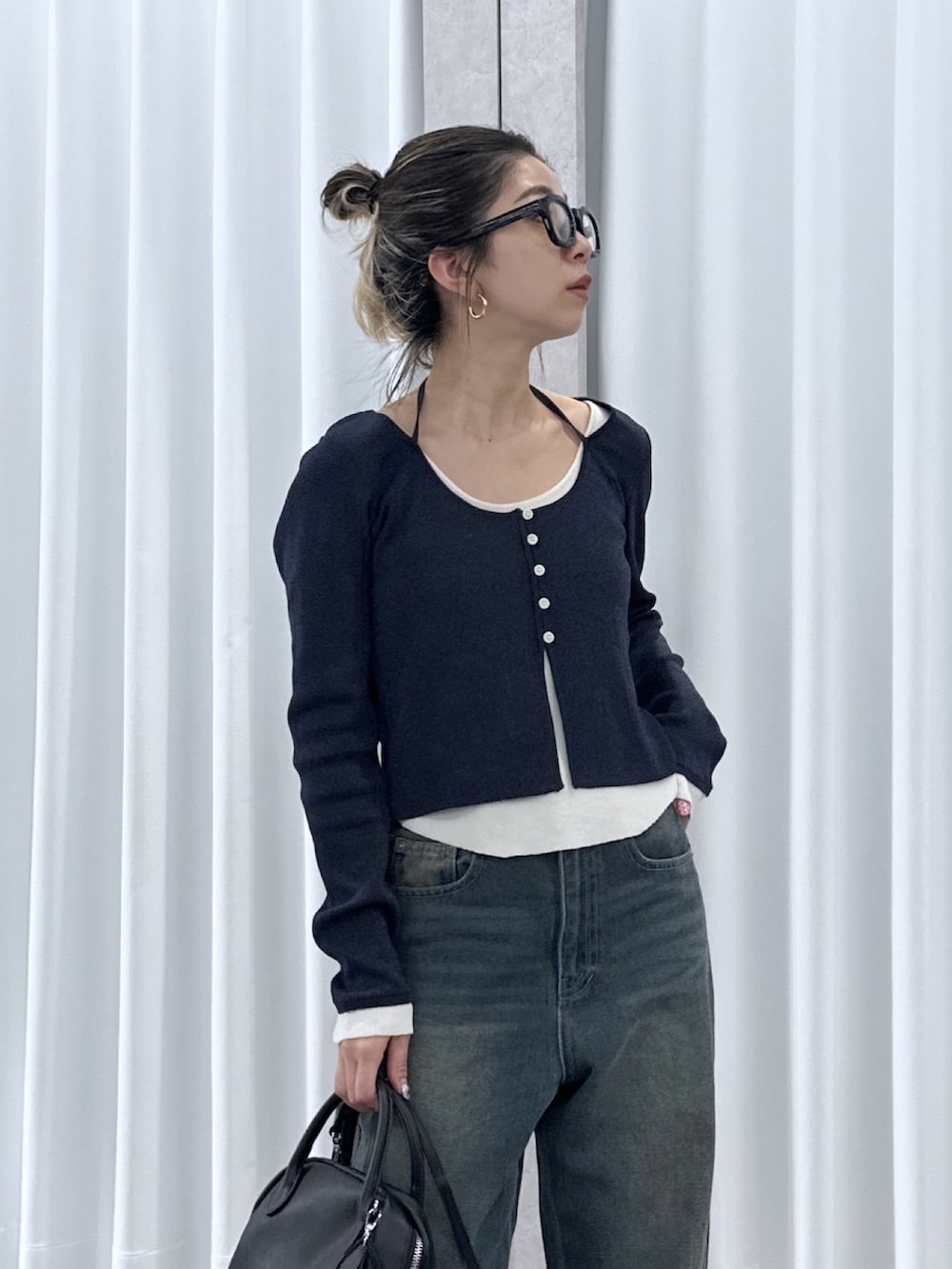 ブルー系のニット/セーター、ブルー系のデニムパンツ、ブラック系のハンドバッグを着用したレディースの春コーディネートの4枚目の写真