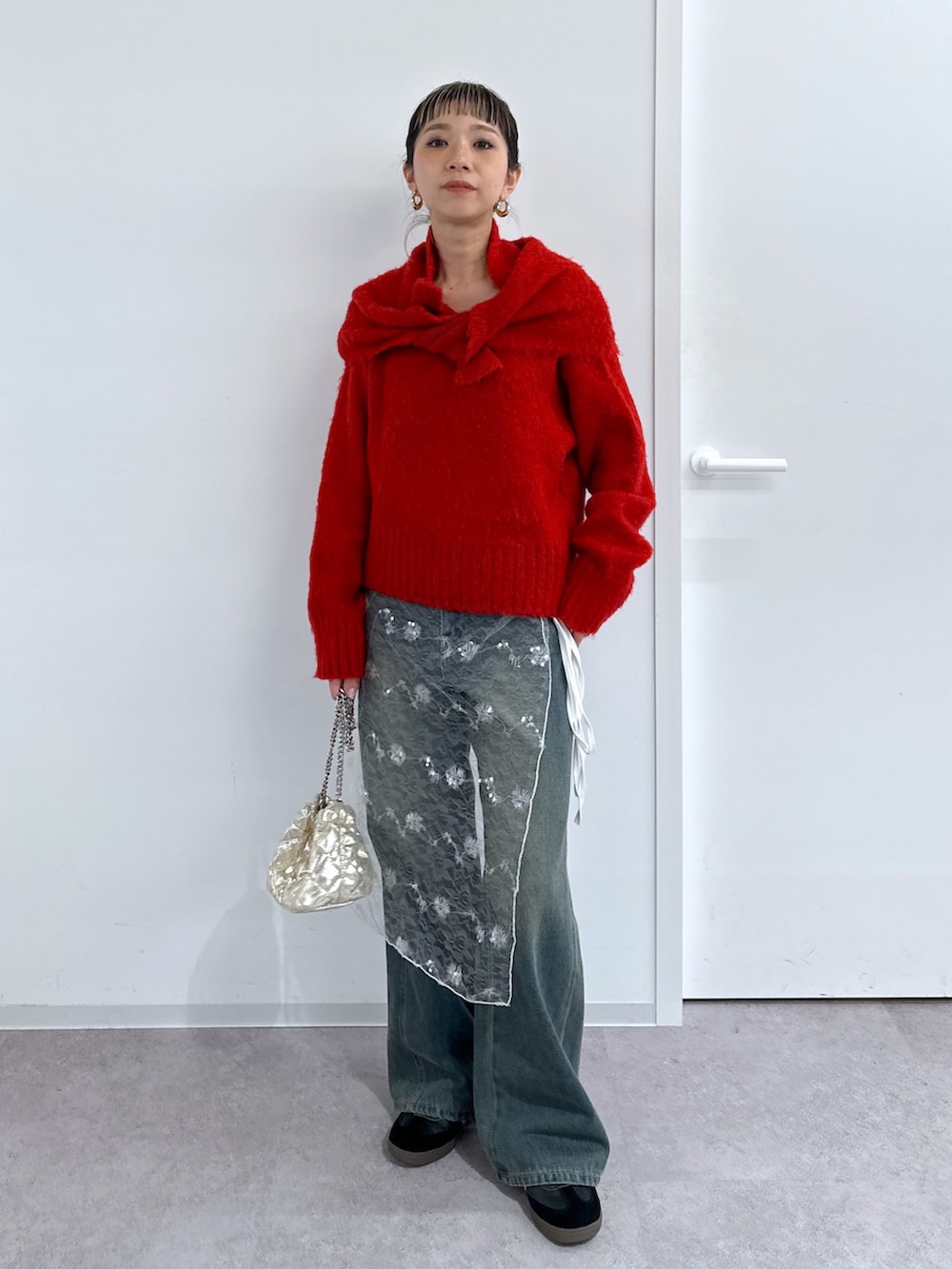 ブラック系のチェスターコート、レッド系のニット/セーター、ブルー系のデニムパンツを着用したレディースの冬コーディネートの4枚目の写真