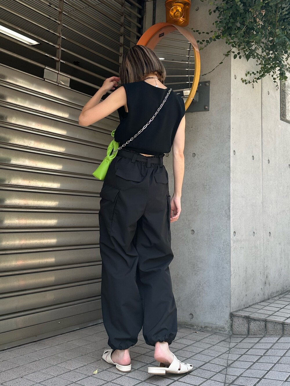 ブラック系のベスト、ブラック系のカーゴパンツ、ホワイト系のサンダルを着用したレディースの夏コーディネートの4枚目の写真