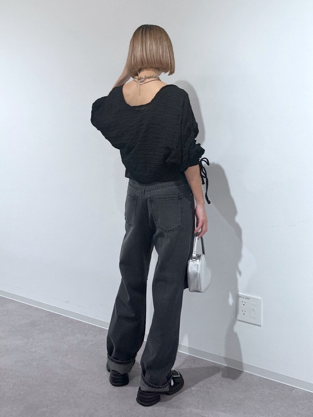 ブラック系のデニムパンツ、シルバー系のショルダーバッグ、ブラック系のサンダルを着用したレディースの春コーディネートの3枚目の写真