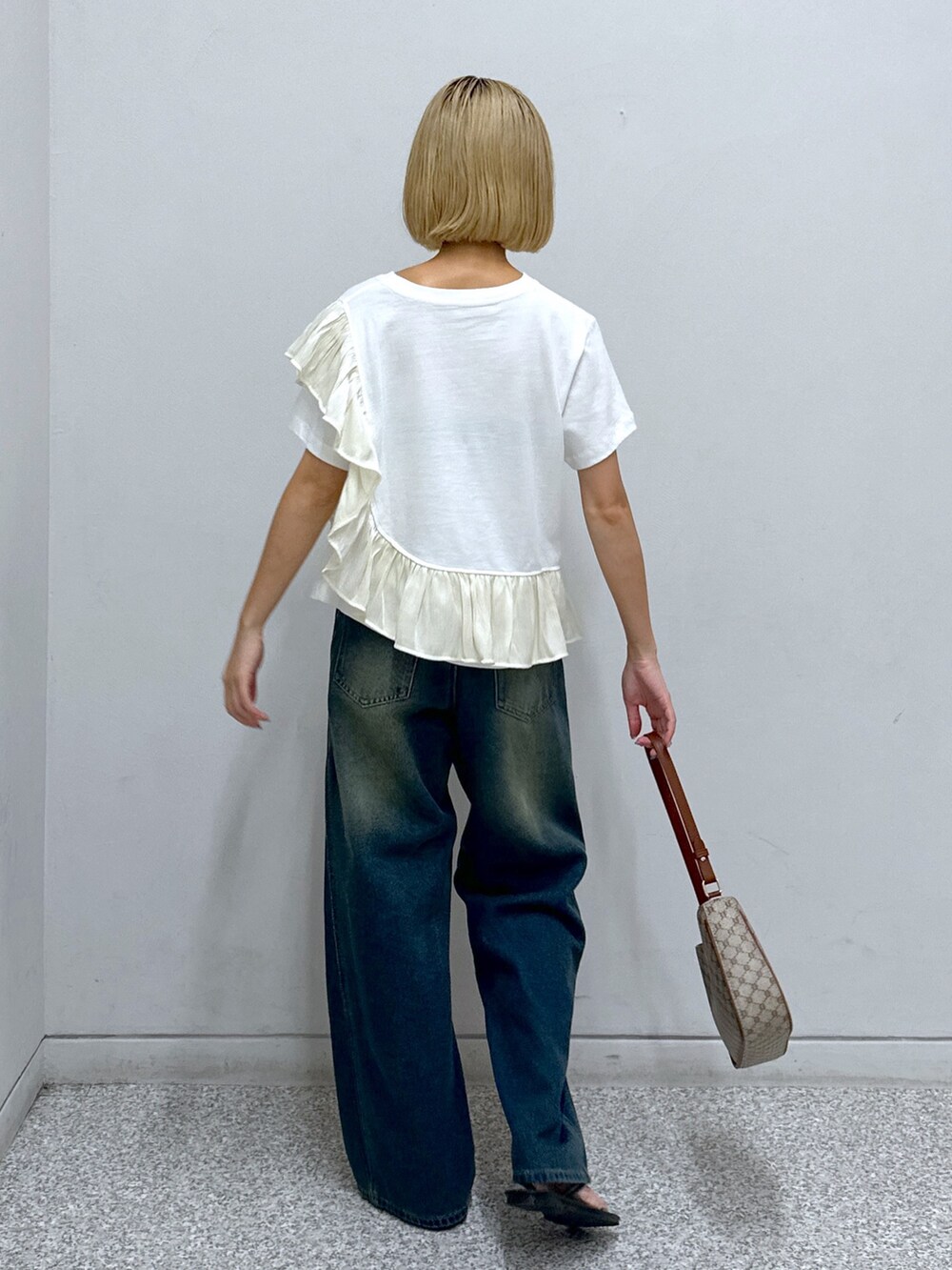 ブルー系のデニムパンツ、ホワイト系のTシャツ/カットソー、ベージュ系のショルダーバッグを着用したレディースの夏コーディネートの3枚目の写真