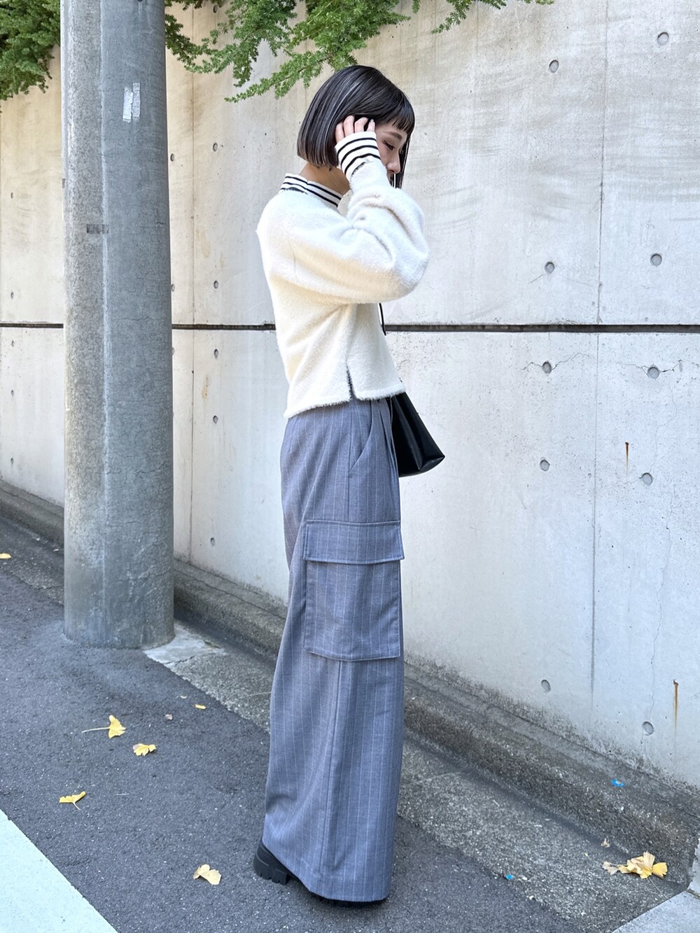 グレー系のスラックス、ブラック系のショルダーバッグ、ホワイト系のニット/セーターを着用したレディースの秋コーディネートの2枚目の写真