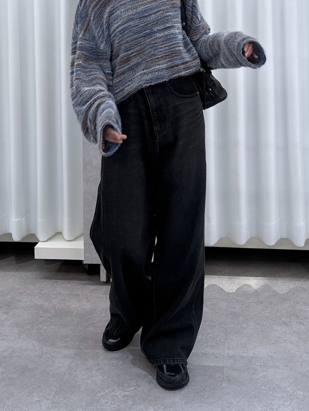 ブルー系のニット/セーター、ブラック系のデニムパンツ、ブラック系のショルダーバッグを着用したレディースの夏コーディネートの5枚目の写真