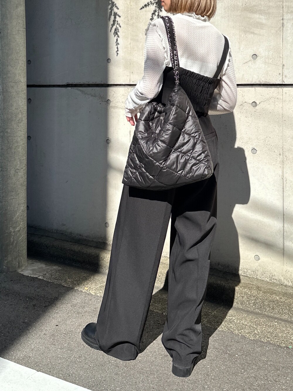 ブラック系のトートバッグ、ホワイト系のTシャツ/カットソー、ブラック系のベストを着用したレディースの秋コーディネートの3枚目の写真