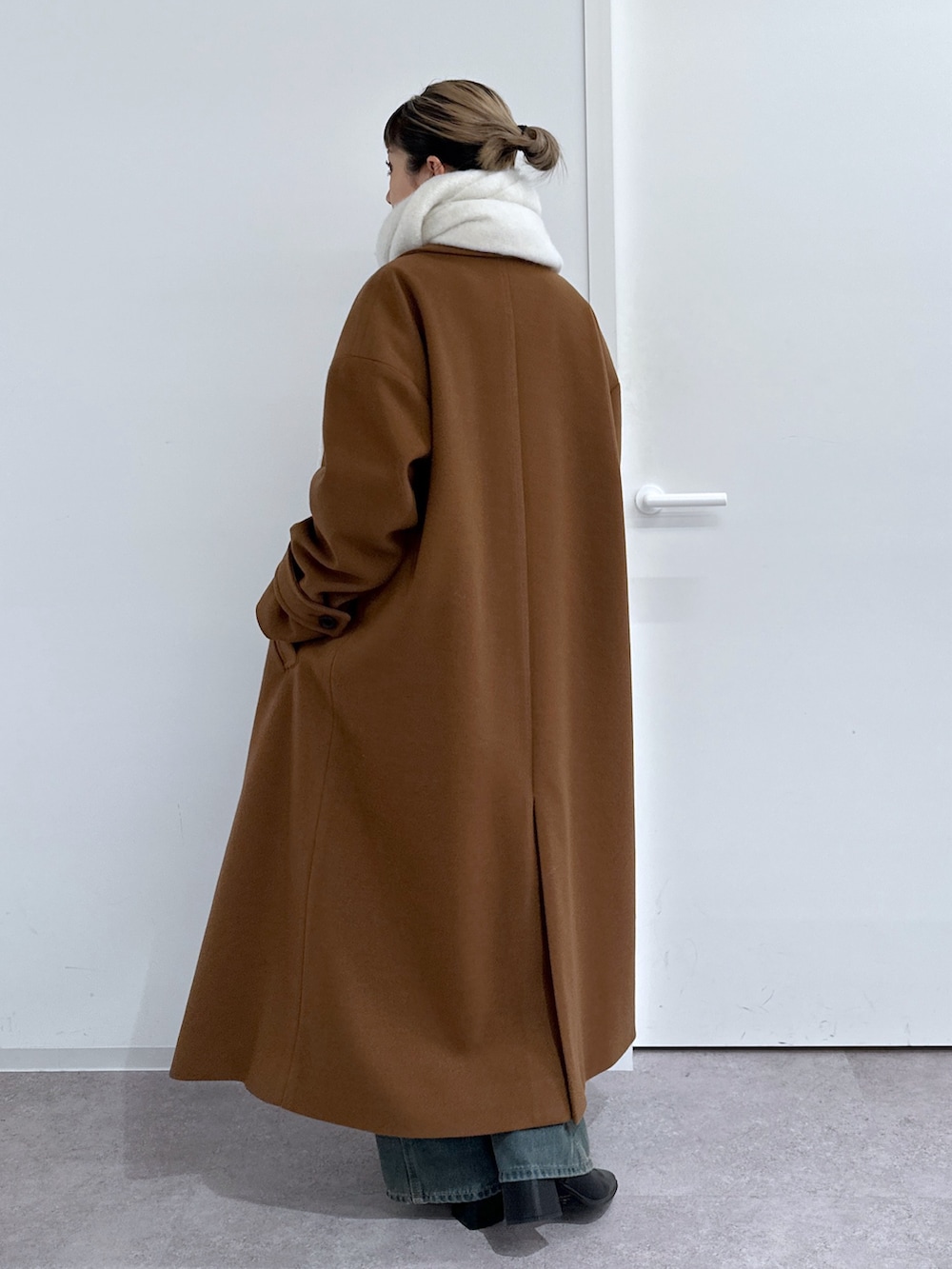 ブラウン系のチェスターコート、ホワイト系のTシャツ/カットソー、グレー系のニット/セーターを着用したレディースの冬コーディネートの3枚目の写真