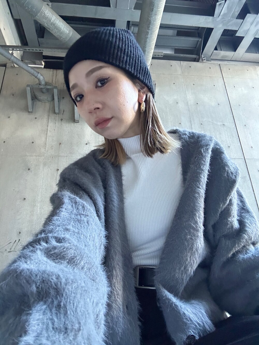 グレー系のカーディガン/ボレロ、ホワイト系のニット/セーター、ブラック系のスラックスを着用したレディースの冬コーディネートの3枚目の写真