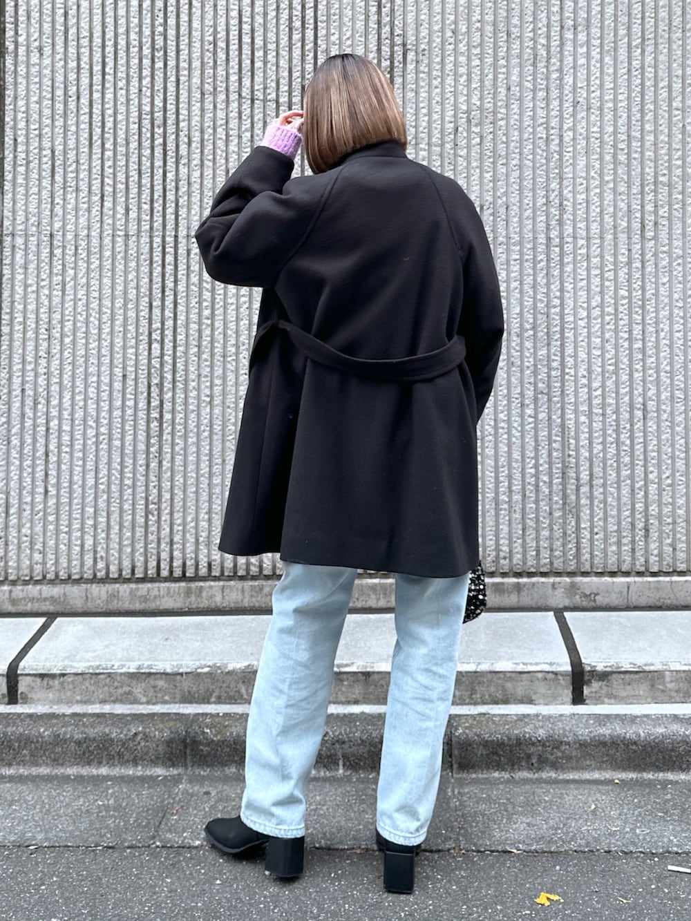 ブルー系のデニムパンツ、ブラック系のステンカラーコートを着用したレディースの冬コーディネートの4枚目の写真